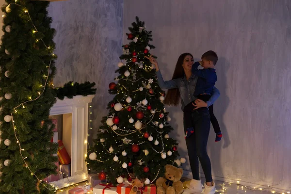 Мать и сын празднуют Новый год у елки с подарками огни Гарланд мандарины — стоковое фото