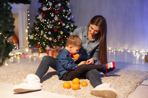 Mother and son celebrate the new year at a Christmas tree with presents lights Garland — Stock Photo, Image