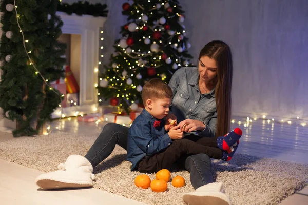 Mère et fils célèbrent la nouvelle année à un arbre de Noël avec des lumières cadeaux Guirlande — Photo