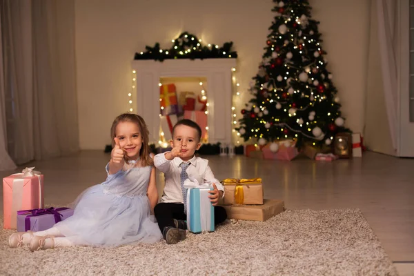 Um menino com uma menina abrir presentes de Natal feriado de ano novo luzes de guirlanda — Fotografia de Stock