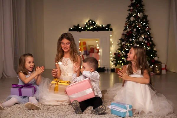 Niños abren regalos de Navidad año nuevo luces de vacaciones chispas — Foto de Stock