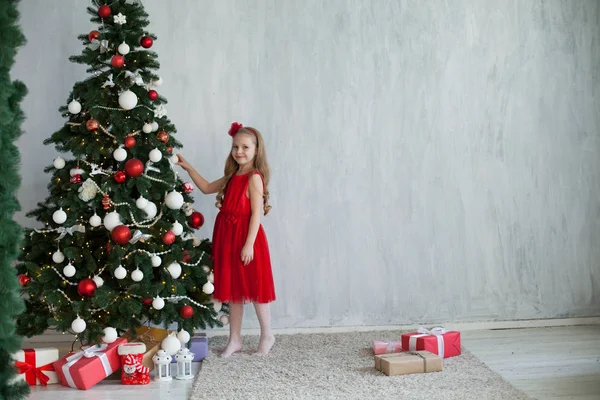 Liten flicka öppnar presenterar nytt år julgran — Stockfoto