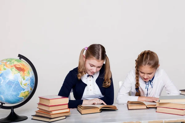 Twee meisjes in de klas leren Les boeken op haar Bureau wereldbol — Stockfoto