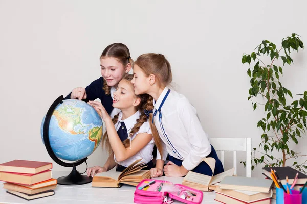 Drie meisjes in de klas studeren geografie bol van planeet aarde — Stockfoto