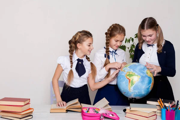 Três meninas em sala de aula estudando geografia globo do planeta Terra — Fotografia de Stock