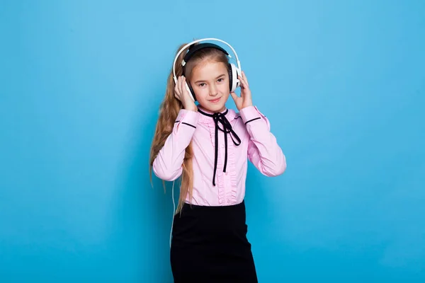 Portrét krásné dívky s sluchátka poslouchat hudbu na modrém pozadí — Stock fotografie