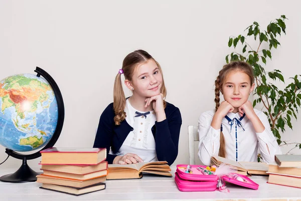 Two girls in the classroom Learn lesson books at her desk globe — Stock Photo, Image