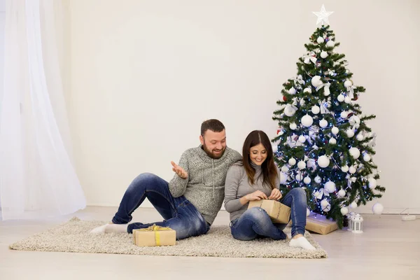 Man och kvinna öppna julklappar på julgran nyår — Stockfoto