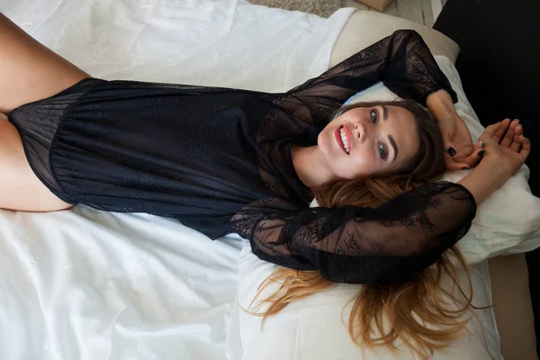 İç çamaşırlı güzel bir kadın yatak odasındaki yatağa uzanıyor. — Stok fotoğraf