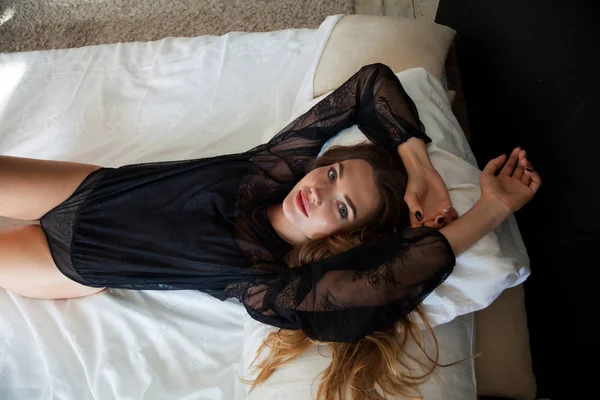 下着姿の美しい女性が寝室のベッドの上に横たわっています — ストック写真
