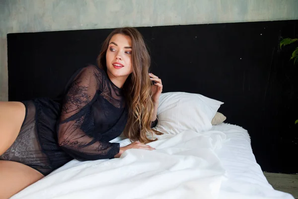 Красива жінка в нижній білизні лежить на ліжку в спальні — стокове фото