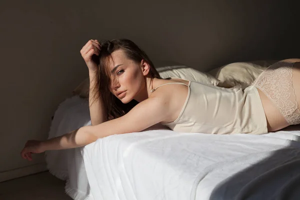 Красивая женщина в нижнем белье лежит на кровати в спальне — стоковое фото