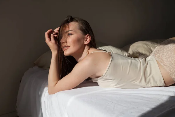 속옷을 입고 침실 침대에 누워 있는 아름다운 여인 — 스톡 사진