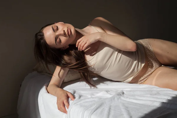 Hermosa mujer en ropa interior se encuentra en la cama en el dormitorio — Foto de Stock