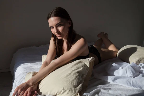 Красива жінка в нижній білизні лежить на ліжку в спальні ранковий сон — стокове фото