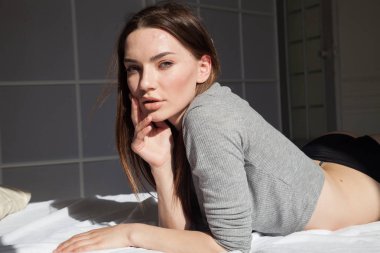 İç çamaşırlı güzel bir kadın yatak odasındaki yatağa uzanıyor.