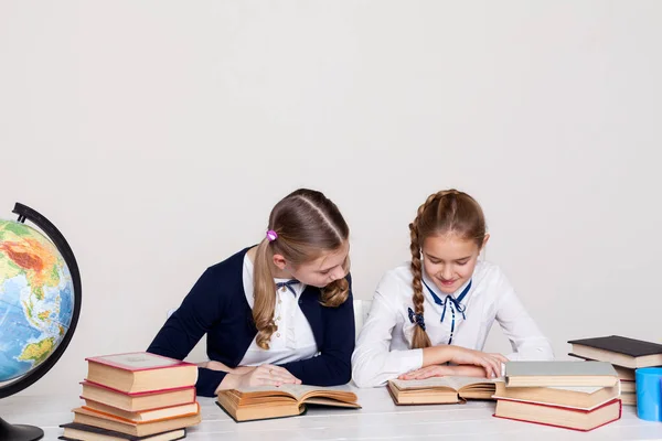 Twee schoolmeisjes meisjes in de klas op haar bureau met boeken-laptops — Stockfoto