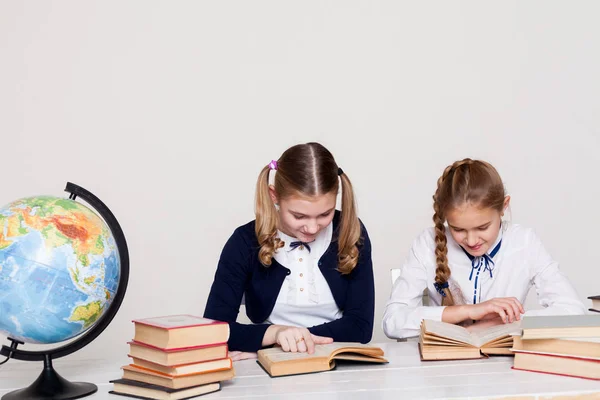 Twee schoolmeisjes meisjes in de klas op haar bureau met boeken-laptops — Stockfoto