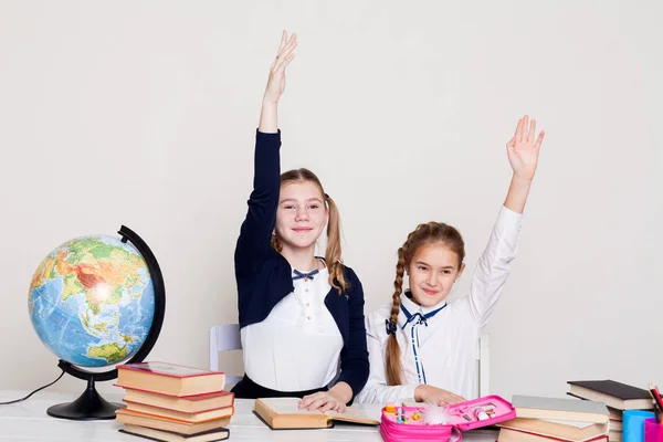 Twee schoolmeisjes meisjes in de klas op haar bureau met boeken hand te beantwoorden — Stockfoto
