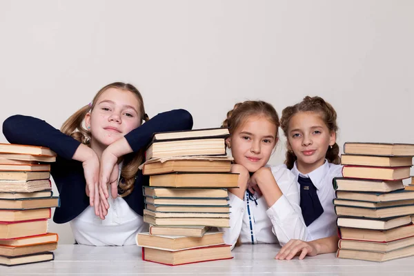 Drie meisjes schoolmeisjes aan een bureau met boeken over de les op school — Stockfoto