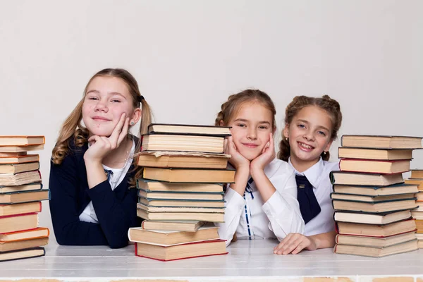 Tři holky školačky u stolu s knihami na lekci ve škole — Stock fotografie