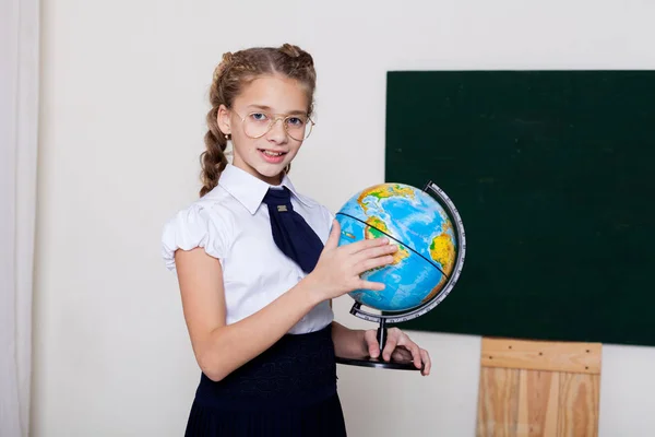 Menina menina da escola em óculos no quadro negro na lição na escola — Fotografia de Stock
