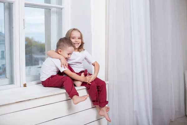 소년과 소녀는 형제와 자매는 창에 창턱에 앉아 — 스톡 사진