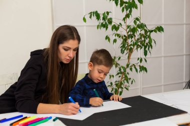 Anne işaretleri masada çizmek için genç çocuk evlat öğretir