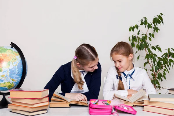Две школьницы в классе за ее столом с книгами тетради — стоковое фото