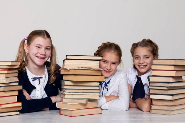 Three girls schoolgirls at a desk with books on the lesson at school — Stock Photo, Image