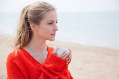 ıssız bir kumlu plajda denize bakarak bir kadın oturur