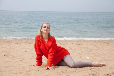 ıssız bir kumlu plajda denize bakarak bir kadın oturur