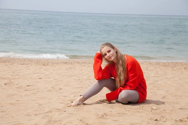 Een vrouw zit op een verlaten zandstrand kijken naar zee — Stockfoto