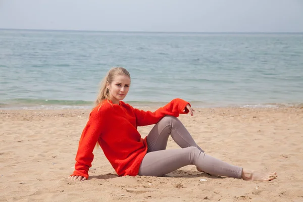 Een vrouw zit op een verlaten zandstrand kijken naar zee — Stockfoto