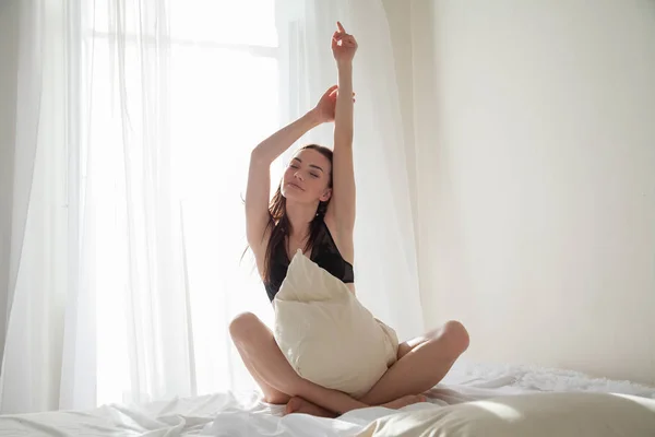 Belle femme en sous-vêtements assis sur un lit avec une chambre d'oreiller — Photo