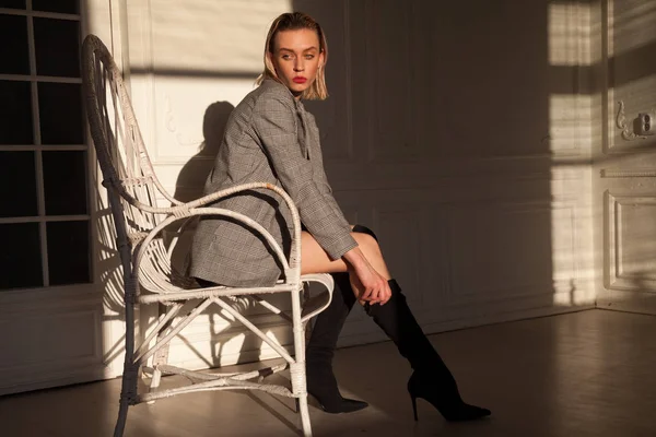 Hermosa mujer de moda en un vestido en un sillón rubia —  Fotos de Stock