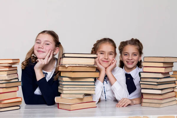 Three girls at school in the classroom for books of knowledge — Stock Photo, Image