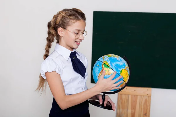 Menina com um globo no quadro negro em uma aula — Fotografia de Stock