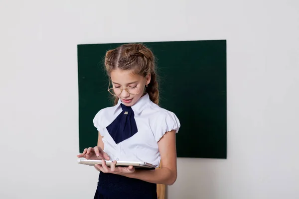 A menina com o tablet no quadro negro em uma aula — Fotografia de Stock