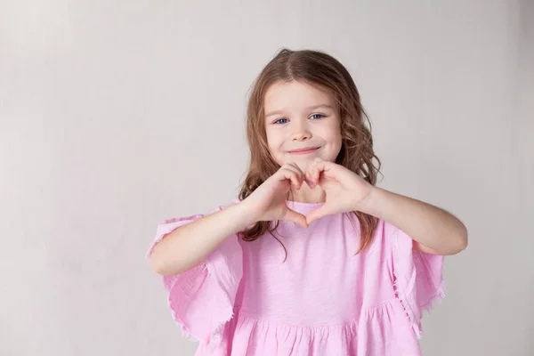 Mała dziewczynka pokazuje ręce symbol serca — Zdjęcie stockowe