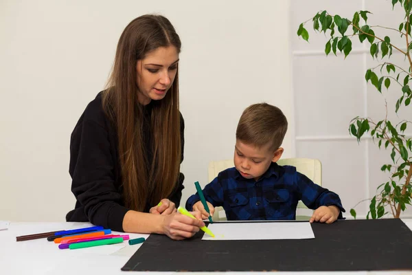 Мать и маленький сын рисует картину за столом — стоковое фото