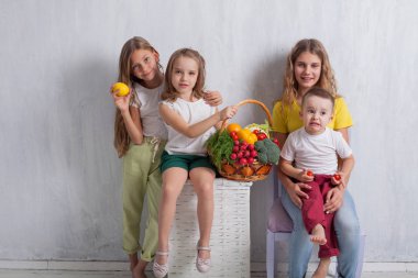 Çocuklar taze sebzelerle oturur sağlıklı meyve yerler.