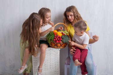 Çocuklar taze sebzelerle oturur sağlıklı meyve yerler.