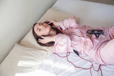 kadın Pembe pijama yatağa dans kulaklık müzik dinlemek