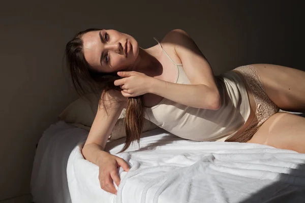 Όμορφη γυναίκα στο εσωρούχων ξαπλωμένος σε ένα κρεβάτι στο υπνοδωμάτιο — Φωτογραφία Αρχείου