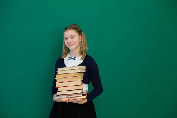 Schulmädchen steht mit Schulbüchern an der Tafel — Stockfoto