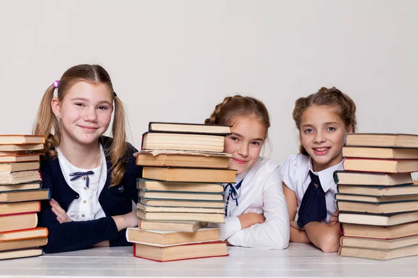 Two girls schoolgirls sit with books at his desk on the lesson at school — Stock Photo, Image