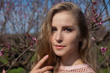 pembe çiçekleri ile baharda çiçekli Şeftali Bahçesi güzel sarışın kadın