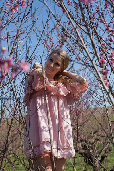 Красива блондинка жінка в квітках персик сад навесні з рожевими квітами — стокове фото