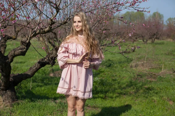 pembe çiçekleri ile baharda çiçekli Şeftali Bahçesi güzel sarışın kadın